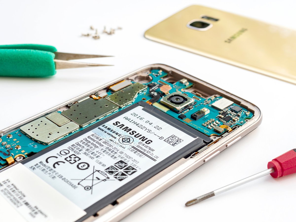 Close-up image of inside disassembled broken Samsung Galaxy S7 edge smartphone preparing to repair with tools