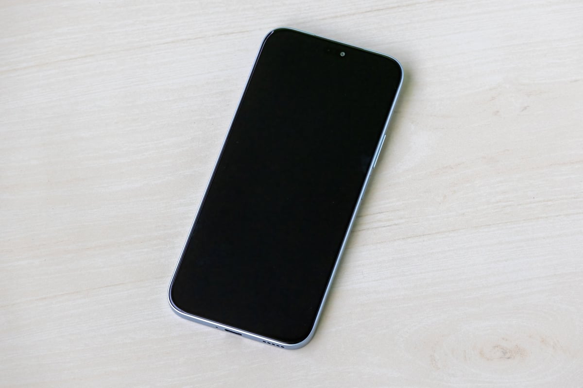 Smartphone with the screen off on light wooden surface. Android mobile phone with black screen.