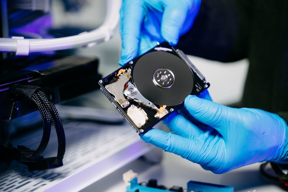 Closeup of technician repairing hard disk for data recovery in modern tech lab