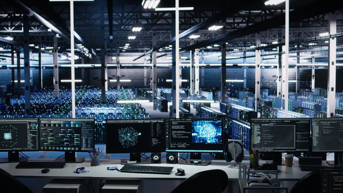 Data center computer systems on desk controlling network resources through AI visualization dashboards, and artificial intelligence programming software mapping infrastructure connections