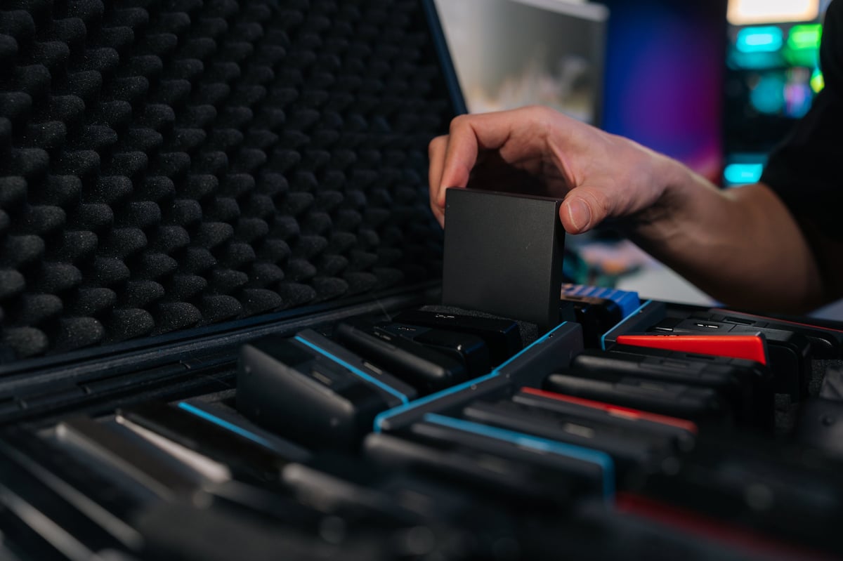 Hand picking up portable external SSD from dedicated slot in protective case