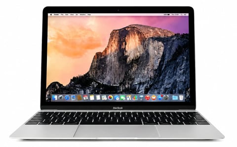 MacBook laptop displaying a scenic mountain landscape with El Capitan on screen against a colorful sunset background